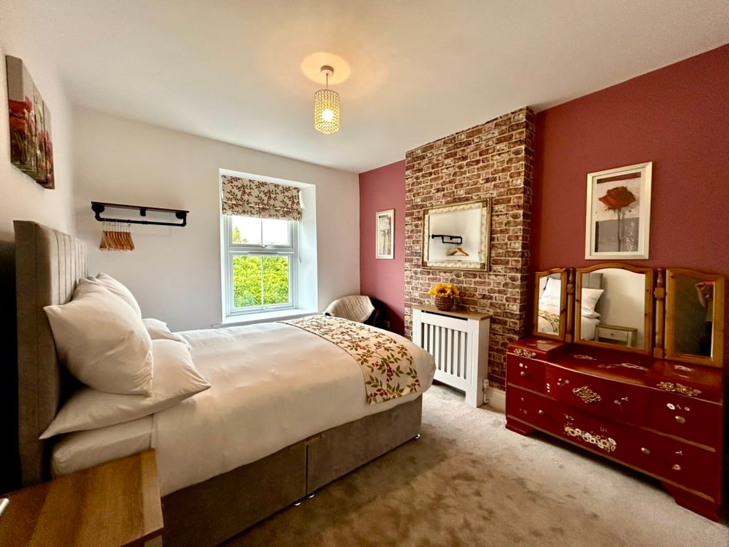 Comfortable double bedroom with red feature wall at Sweet Cottage